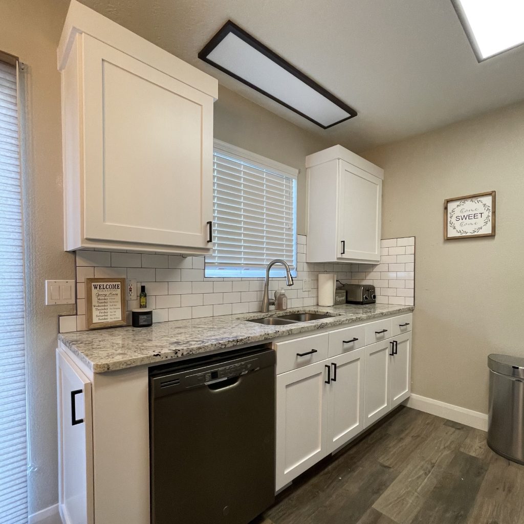 Modern kitchen with white cabinets and appliances.